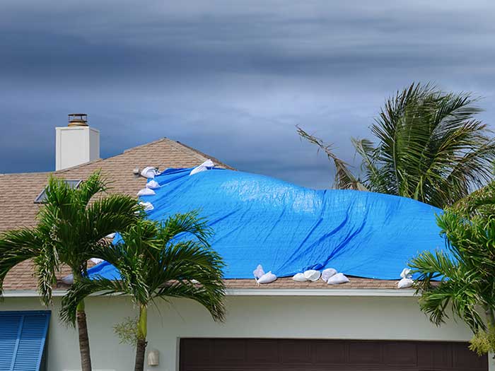 Roof covered in blue tarp from storm damage